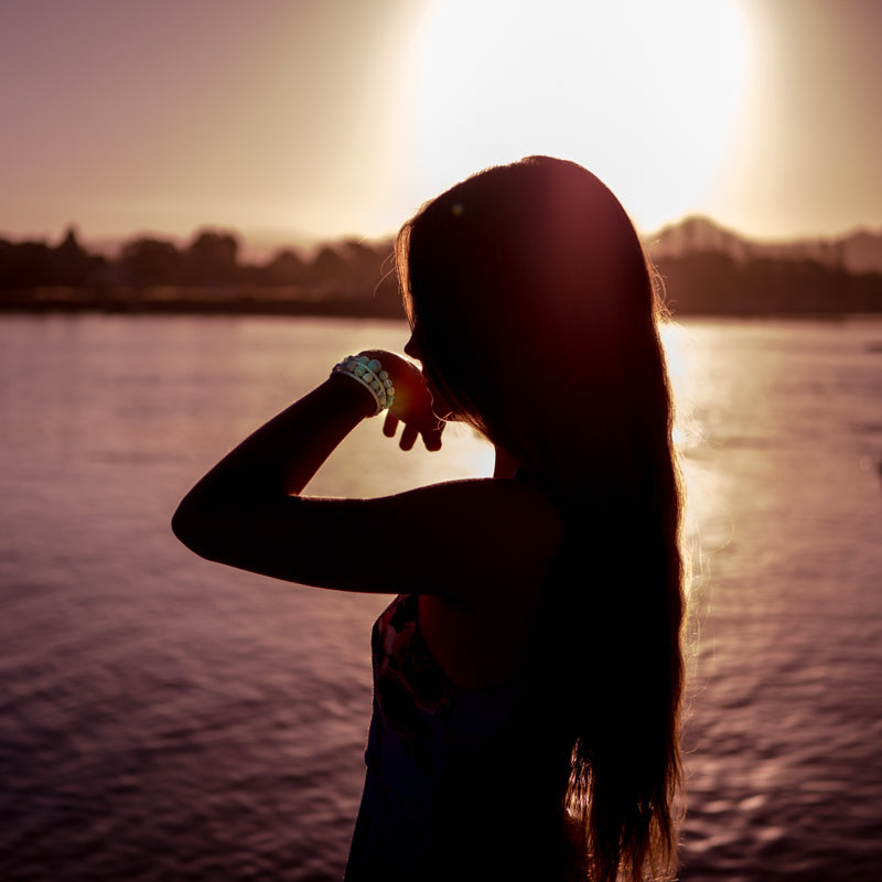 Silhouette of a girl smelling a Kylee Joy hand made crystal and lava stone essential oil bracelets.